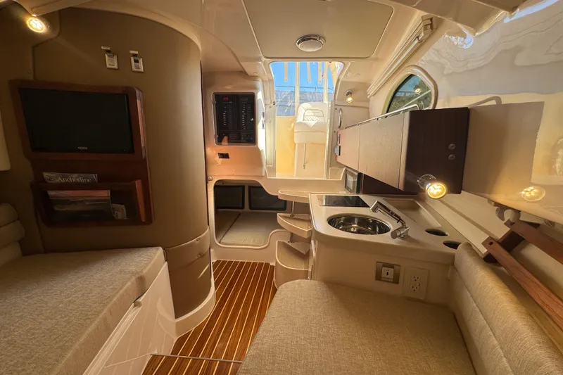 Slide: The Image of 2024 Grady-White Marlin 300 interior with kitchenette, seating, and wooden flooring. - 24