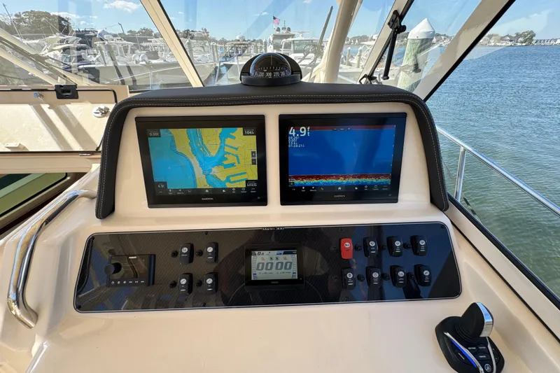 Slide: The Image of 2024 Grady-White Marlin 300 boat cockpit with navigation screens, docked at marina. - 66
