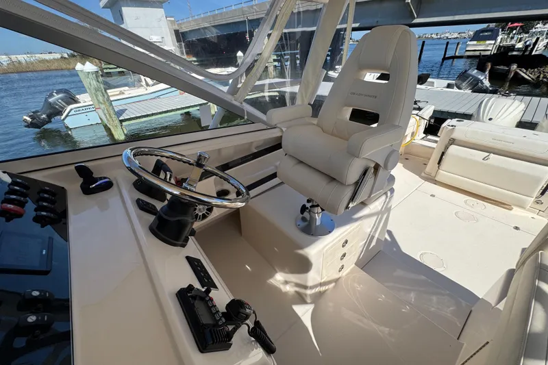 Slide: The Image of 2024 Grady-White Marlin 300 helm with navigation screens and steering wheel, dockside view. - 75