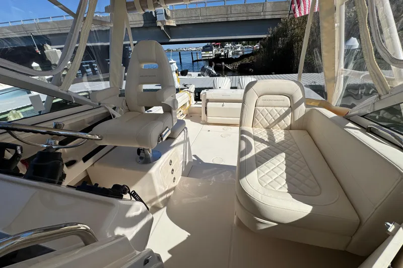 Slide: The Image of 2024 Grady-White Marlin 300 helm with open storage, dual screens, and marina view. - 80