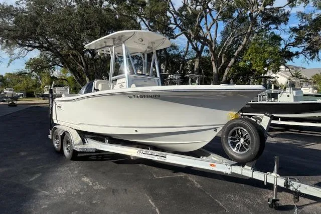 The Image of 2025 Sea Hunt Ultra 219 boat on trailer, parked outdoors, surrounded by trees. - 0