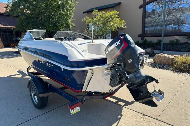 Slide: The Image of 2013 Larson LX 180S OB boat with Evinrude engine on trailer, outdoors. - 2