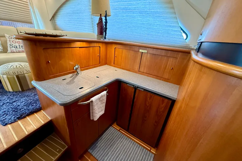 Slide: The Image of 2006 Tiara Yachts 3900 Convertible interior with wooden cabinetry and compact kitchen area. - 19