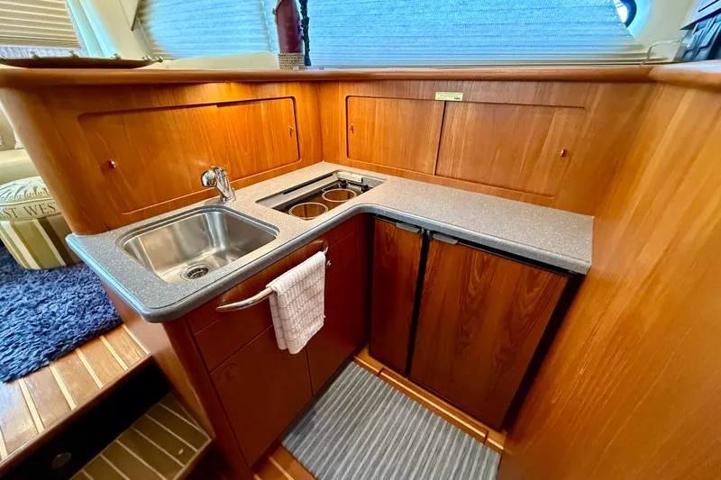 Slide: The Image of 2006 Tiara Yachts 3900 Convertible kitchen with wood cabinetry and stainless steel sink. - 20