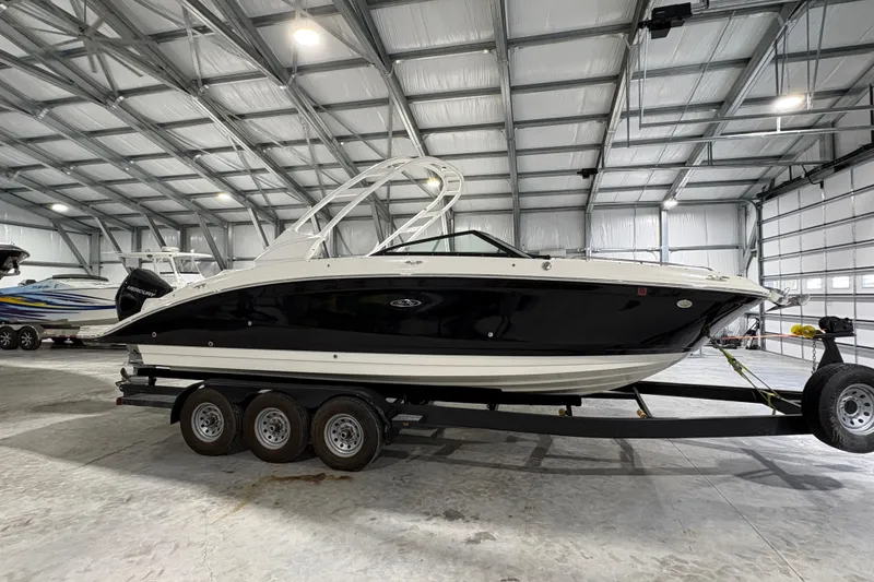 Slide: The Image of 2022 Sea Ray SDX 270 Outboard boat on trailer, parked in a lot with trees. - 2