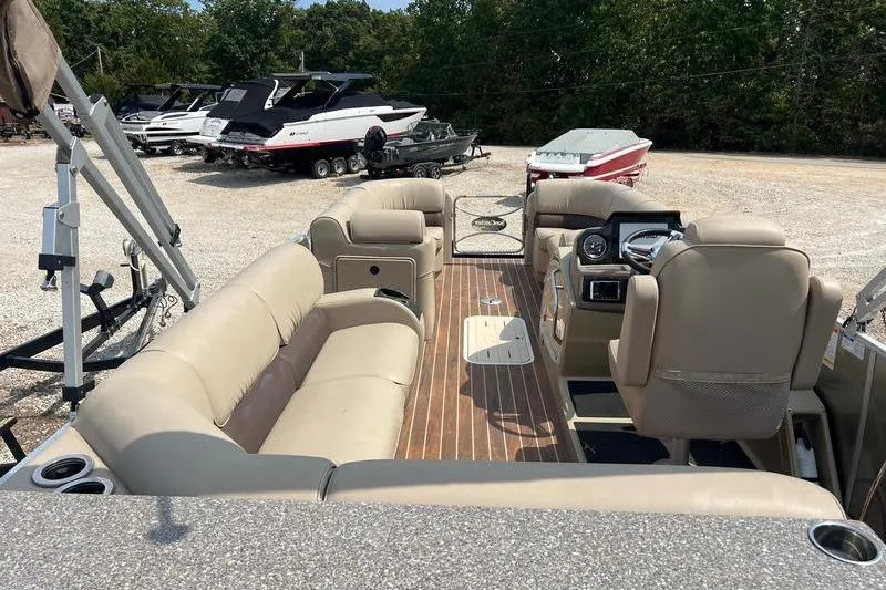 Slide: The Image of 2018 SunChaser 326 pontoon boat with beige seating and wood flooring, parked outdoors. - 1