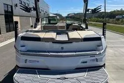Slide: The Image of 2025 MasterCraft NXT22 boat, rear view, parked outdoors on a sunny day. - 14