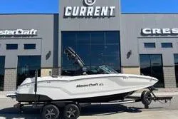 Slide: The Image of 2025 MasterCraft NXT22 boat on trailer outside dealership. - 15