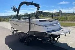 Slide: The Image of 2025 MasterCraft NXT22 boat on trailer, parked outdoors under clear sky. - 3