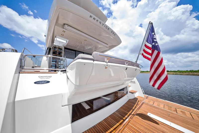 Slide: The Image of 2017 Prestige 560 Flybridge yacht with American flag, docked under a blue sky. - 13