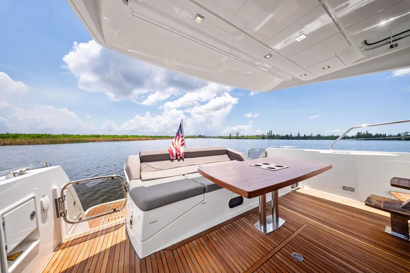 Slide: The Image of Prestige 560 Flybridge 2017 yacht deck with seating, table, and scenic water view. - 17