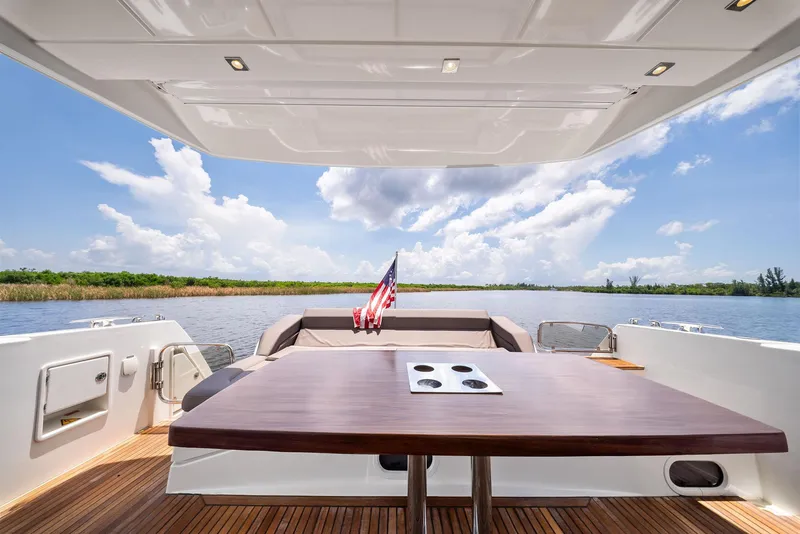 Slide: The Image of Prestige 560 Flybridge 2017 yacht deck with table, scenic water view, and American flag. - 18