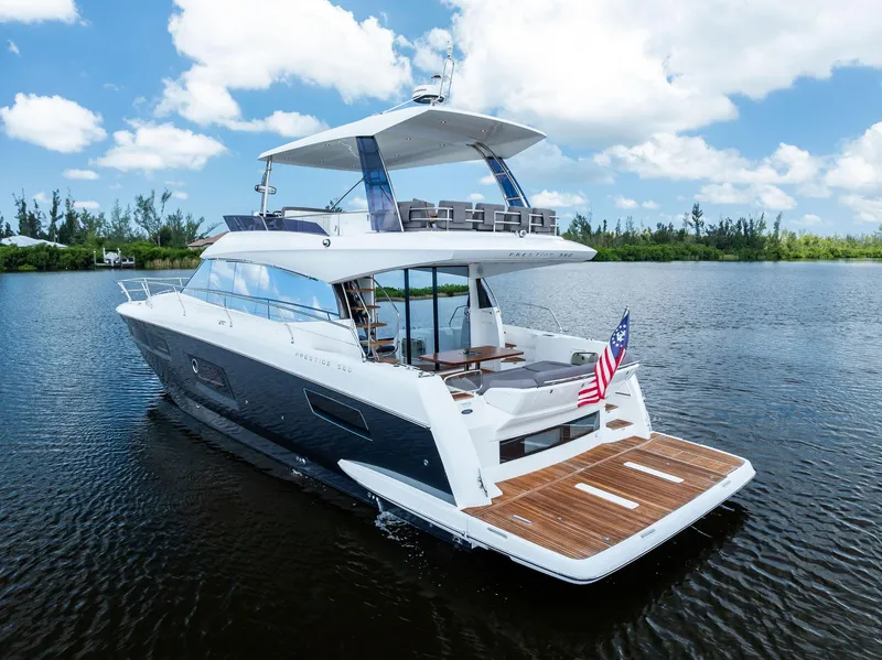 Slide: The Image of 2017 Prestige 560 Flybridge yacht cruising on a serene lake under a blue sky. - 2