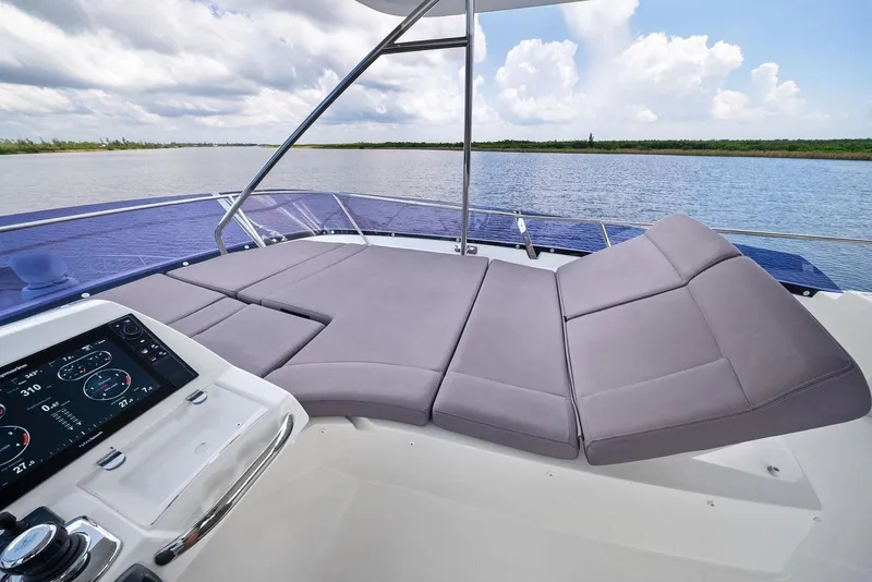 Slide: The Image of Prestige 560 Flybridge 2017 yacht with luxurious seating and control panel, overlooking serene waters. - 26