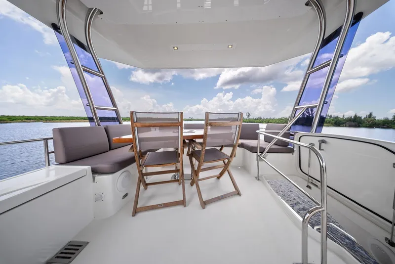 Slide: The Image of Prestige 560 Flybridge 2017 yacht deck with seating, table, and scenic water view. - 28