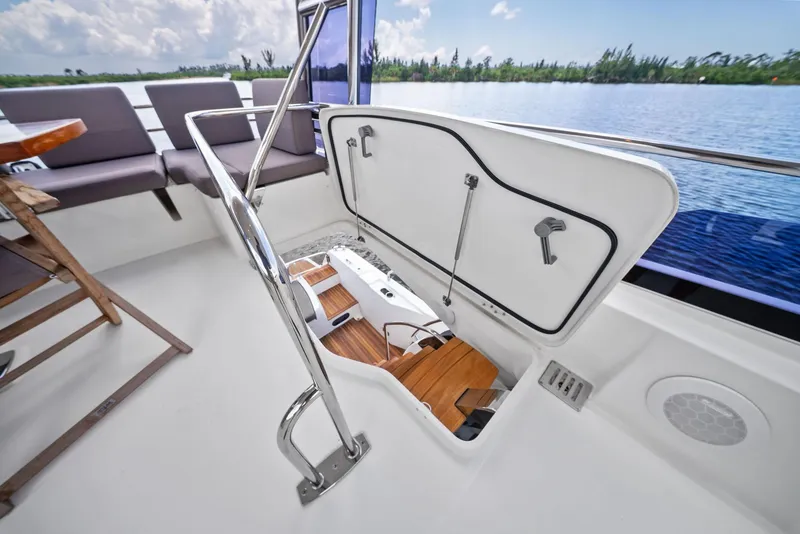 Slide: The Image of Prestige 560 Flybridge 2017 yacht with open storage compartment, overlooking serene water and lush greenery. - 31