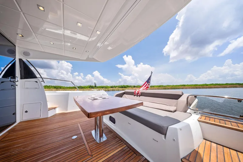 Slide: The Image of Prestige 560 Flybridge 2017 yacht deck with seating, table, and American flag. - 32