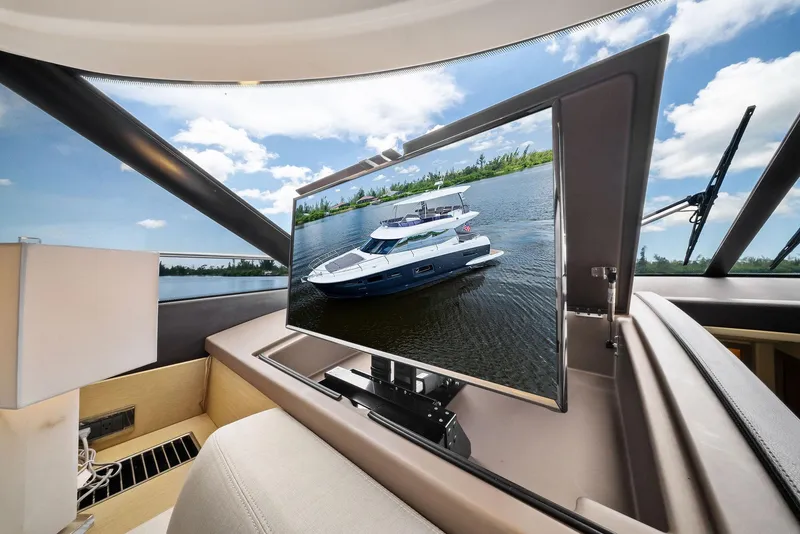 Slide: The Image of 2017 Prestige 560 Flybridge yacht interior with TV displaying exterior view. - 43