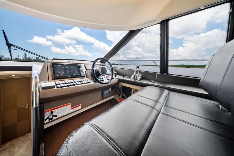 Slide: The Image of 2017 Prestige 560 Flybridge helm with leather seating, modern controls, and scenic water view. - 47