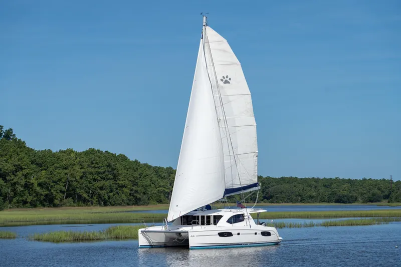 The Image of 2016 Leopard 44 Owners Version catamaran sailing on calm water with lush green shoreline. - 0