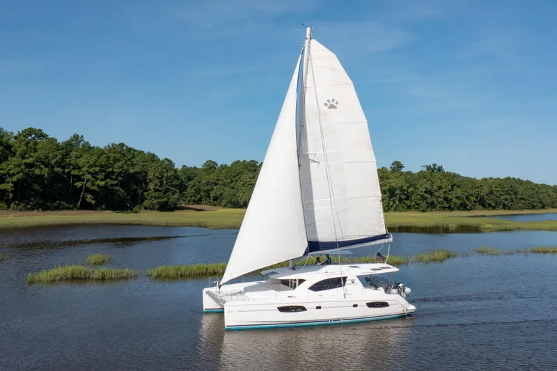 Slide: The Image of 2016 Leopard 44 Owners Version catamaran sailing on a calm river with lush greenery. - 3