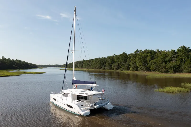 Slide: The Image of 2016 Leopard 44 Owners Version catamaran sailing on a serene river with lush greenery. - 4