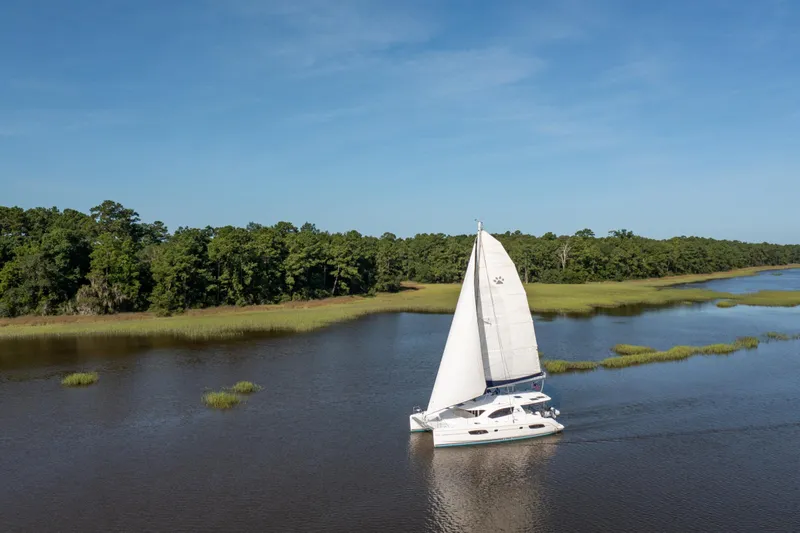 Slide: The Image of Sailing catamaran Leopard 44 cruising on a serene river, surrounded by lush greenery. - 5