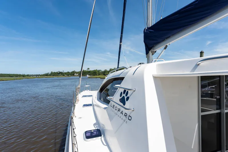 Slide: The Image of 2016 Leopard 44 Owners Version catamaran sailing on a calm river under a clear blue sky. - 7