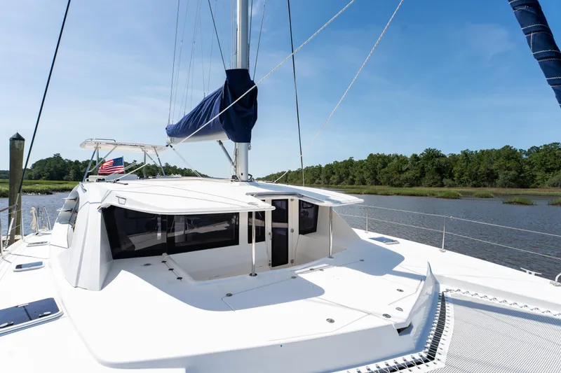 Slide: The Image of 2016 Leopard 44 Owners Version catamaran on a serene river with lush greenery. - 8