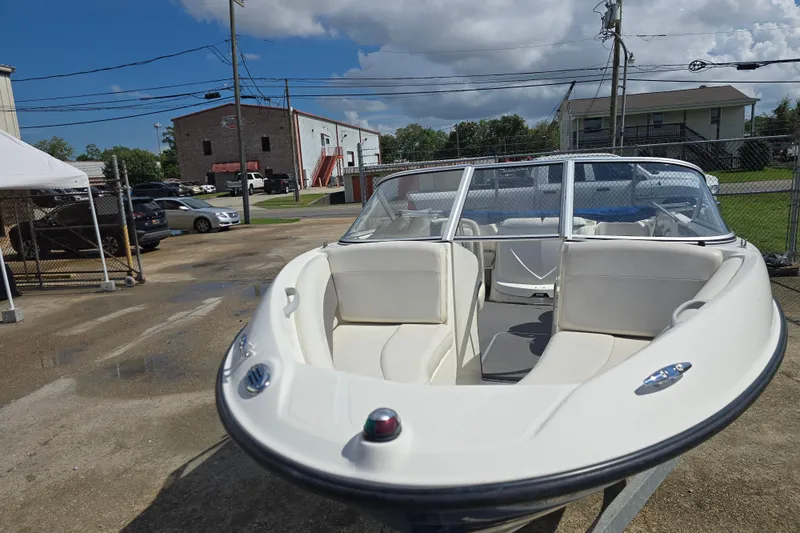Slide: The Image of 2010 Bayliner 185 Bowrider boat with white interior, parked outdoors under a cloudy sky. - 6