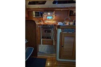Slide: The Image of 1999 Caliber 40LRC yacht kitchen with stove, microwave, and wooden cabinetry. - 23