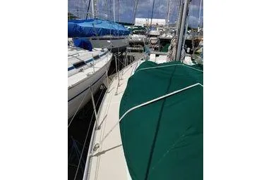 Slide: The Image of 1999 Caliber 40LRC sailboat docked, featuring green deck cover and marina background. - 8