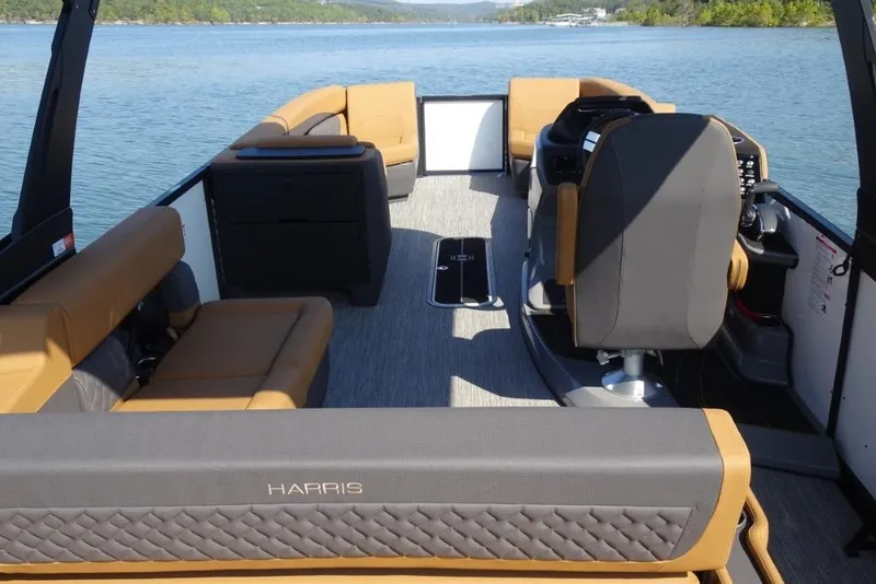 Slide: The Image of 2026 Harris Sunliner 250 pontoon boat interior with tan seating on a serene lake. - 10