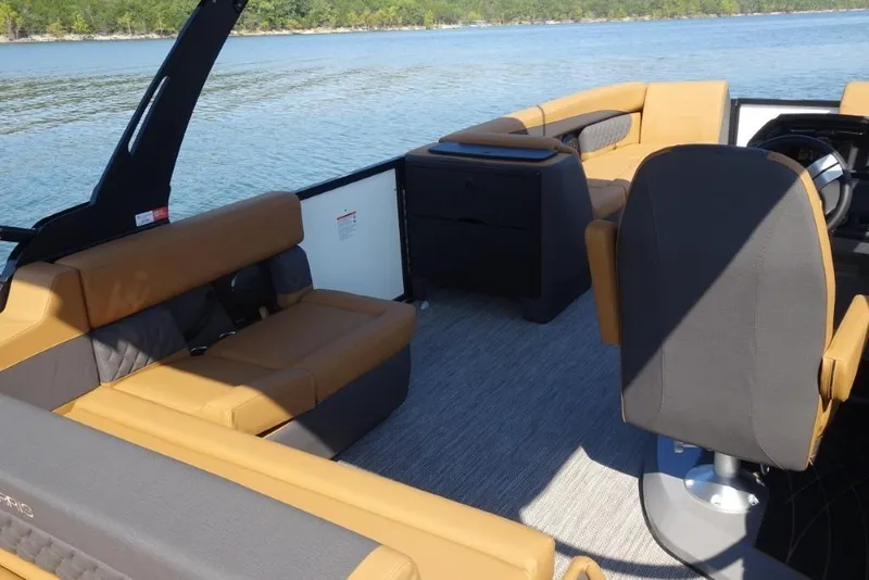 Slide: The Image of 2026 Harris Sunliner 250 boat interior with tan and gray seating on a lake. - 11