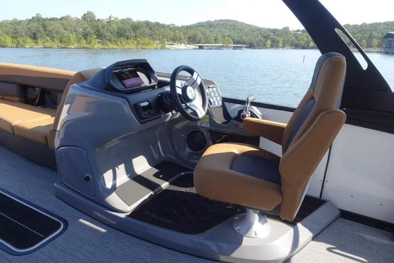 Slide: The Image of 2026 Harris Sunliner 250 boat interior with captain's chair and control panel on a scenic lake. - 13