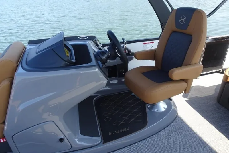 Slide: The Image of Captain's chair and helm of 2026 Harris Sunliner 250 boat, overlooking water. - 17