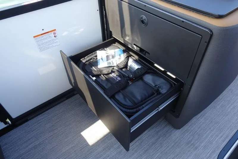 Slide: The Image of Open storage drawer in 2026 Harris Sunliner 250 boat, containing various items. - 19