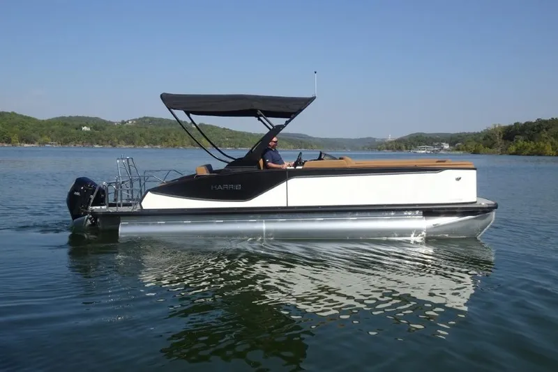 Slide: The Image of 2026 Harris Sunliner 250 pontoon boat cruising on a scenic lake. - 2