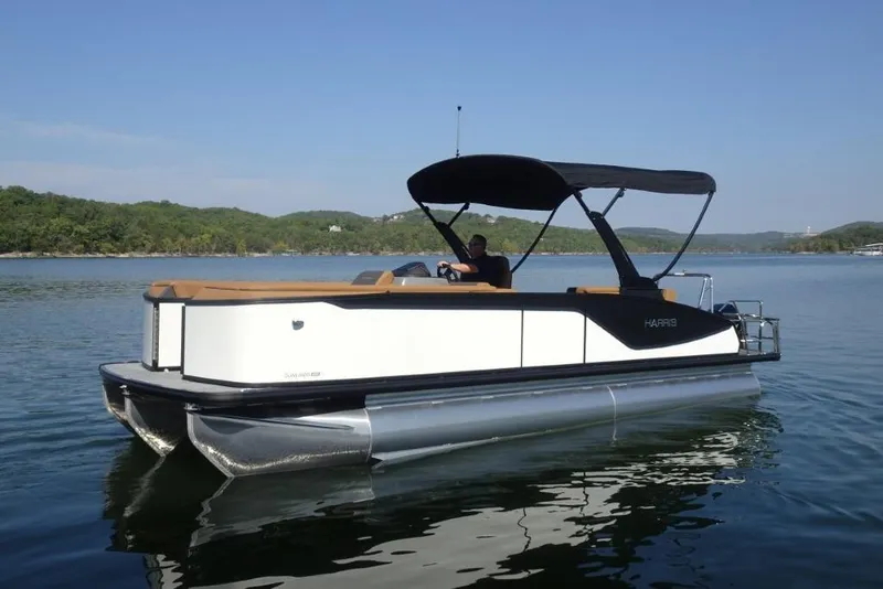 Slide: The Image of 2026 Harris Sunliner 250 pontoon boat on a serene lake with lush green hills. - 5