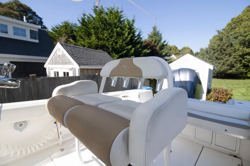 Slide: The Image of 2015 Edgewater 245CC boat interior with cushioned seating and outdoor background. - 11
