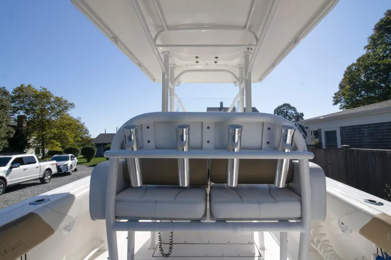 Slide: The Image of 2015 Edgewater 245CC boat interior with rod holders and seating, parked outdoors. - 13
