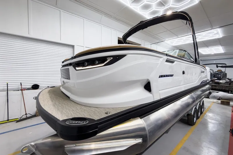 Slide: The Image of 2026 Godfrey Sanpan 27' Tritoon boat in showroom, featuring sleek design and modern amenities. - 12