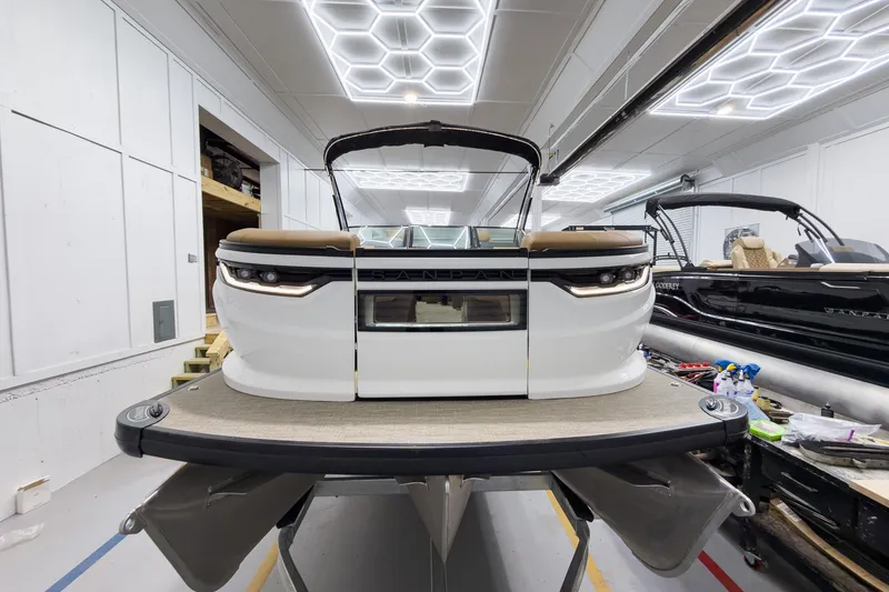 Slide: The Image of 2026 Godfrey Sanpan 27' Tritoon boat in showroom, featuring modern design and twin ultra lounge. - 4