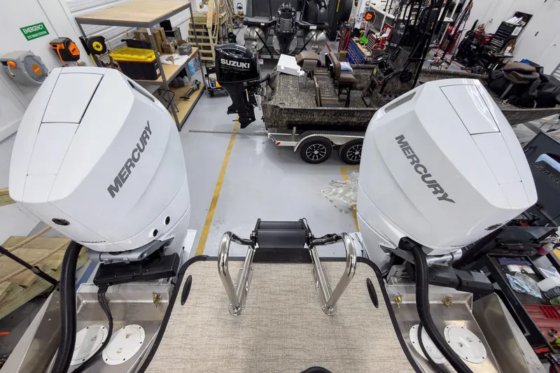 Slide: The Image of Twin Mercury outboard engines on a 2026 Godfrey Sanpan 27' Tritoon in a workshop. - 43