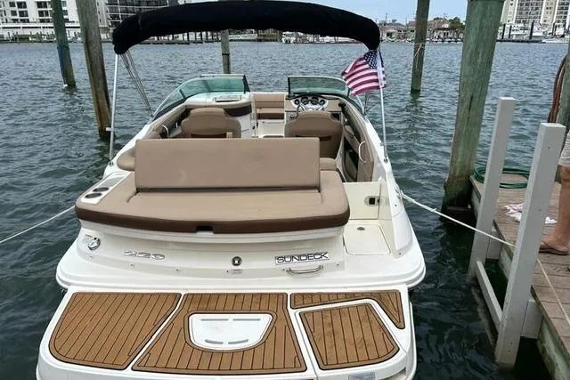 Slide: The Image of 2016 Sea Ray 220 Sundeck boat docked, featuring spacious seating and American flag. - 10
