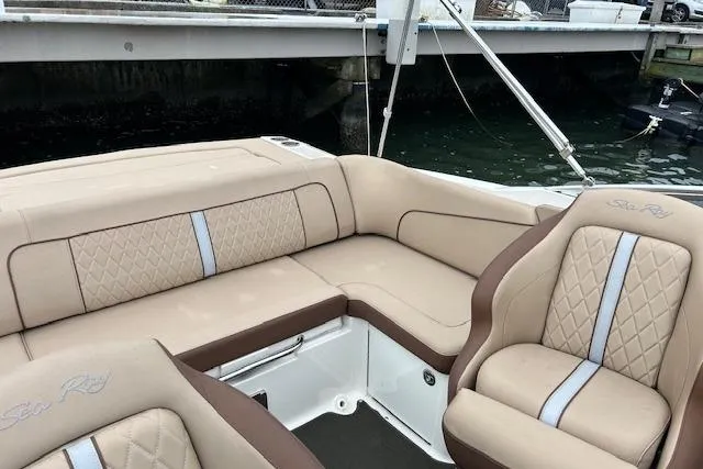 Slide: The Image of 2016 Sea Ray 220 Sundeck interior with beige and brown seating, docked by water. - 5