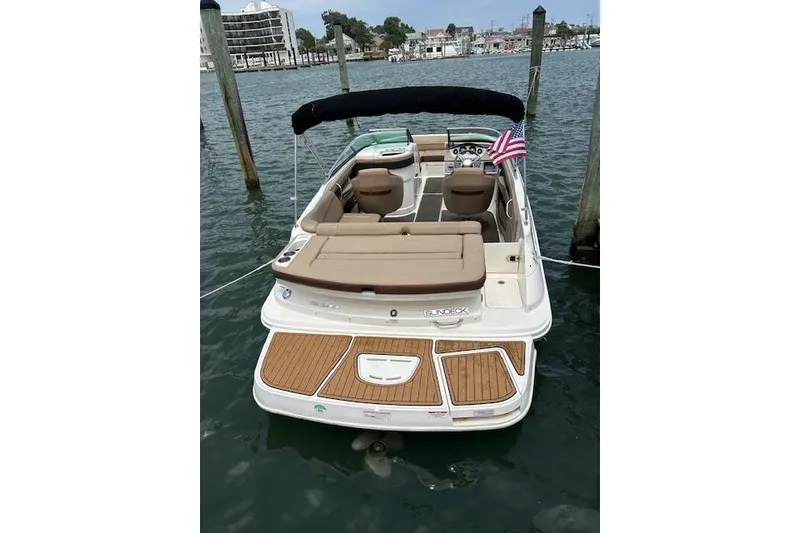 Slide: The Image of 2016 Sea Ray 220 Sundeck boat docked, featuring spacious seating and American flag. - 8