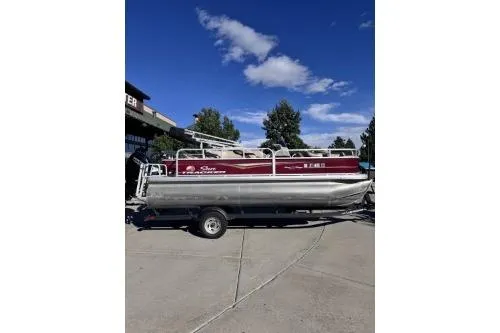 Slide: The Image of 2022 Sun Tracker Bass Buggy 18 DLX pontoon boat on trailer, outdoors under blue sky. - 7