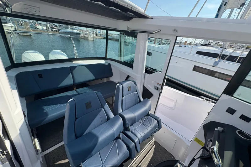Slide: The Image of 2025 Axopar 29 XC Cross Cabin interior with blue seating, docked at marina. - 49