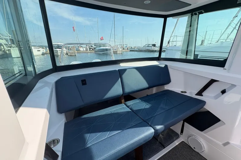 Slide: The Image of Interior of 2025 Axopar 29 XC Cross Cabin with blue seating and marina view. - 50